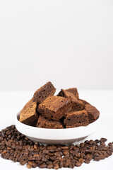 Chocolate cake sliced into squares in a white plate, brownie and coffee beans, space for text