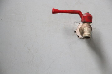 tap with red handle on wall