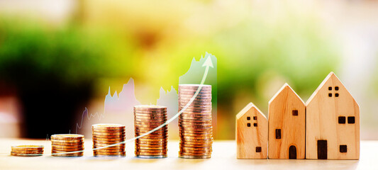 stacking coins with rising graph and wooden house model on wooden table, saving money for buying house	