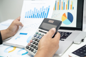Asian accountant working and analyzing financial reports project accounting with chart graph in modern office, finance and business concept.