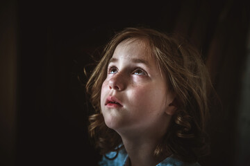a little girl sits alone in a dark hallway. fear, loneliness