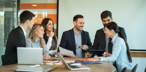 Group of young business people working and communicating while sitting at the office desk together in the conference room