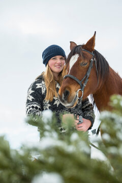 Portrait of a teenage girl with horse in farmland during winter, Bavaria, Germany