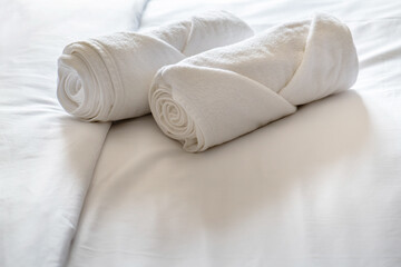 Fototapeta na wymiar Soft pillows and white towel on clean white bed. Pillows bed with bedding sheets in bedroom. Bed sheets and pillows messed. Hotel, resort or home can relax on bed for deep sleep.