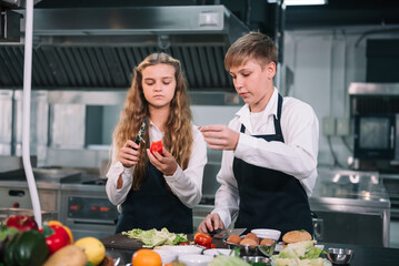 Two student boy and girl enjoy studying cooking class at school kitchen.