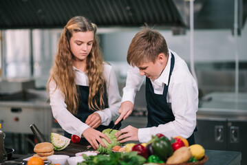Two student boy and girl enjoy studying cooking class at school kitchen.