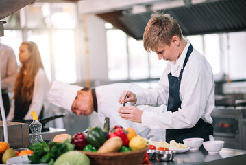 Group of diverse student chef learning cooking class in the kitchen. Mature asian teacher teaching diverse chef students at school.