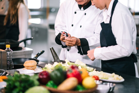 Group Of Diverse Student Chef Learning Cooking Class In The Kitchen. Mature Asian Teacher Teaching Diverse Chef Students At School.