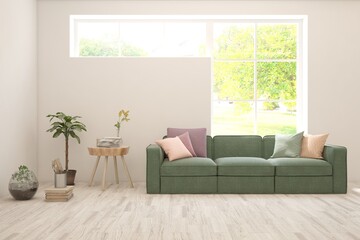 Fototapeta premium White living room with sofa and summer landscape in window. Scandinavian interior design. 3D illustration
