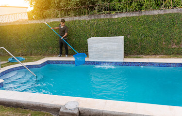 Fototapeta na wymiar Maintenance person cleaning a swimming pool with skimmer, Worker cleaning a swimming pool with skimmer. Swimming pool cleaning and maintenance concept