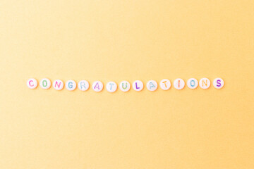 Word Congratulations. Quote made of white round beads with colorful letters on a gold glittering...