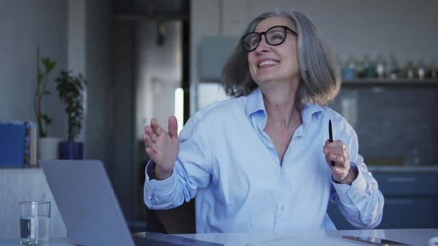 Extremely excited mature woman shaking her head and waving hair, moving hands, dancing, actively moving to the music rhythm, celebrating good news or success, big luck