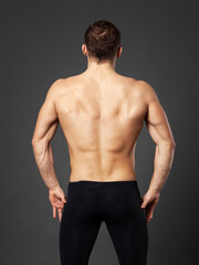 Obraz premium Portrait of a young ballet dancer photographed from behind, standing in front of a gray background.