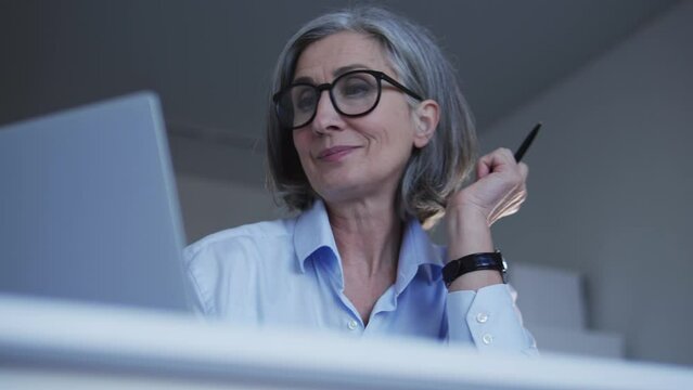 Female redactor with stylish hairstyle typing article on laptop in her office