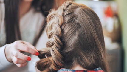 The girl makeup artist makes a braid for the model.