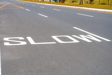 "Slow" written on the asphalt of a quiet street. Empty road with slow down text