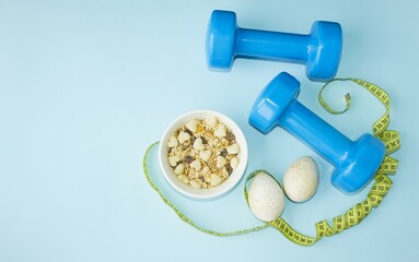 Sports lifestyle, balanced diet.  On a blue background, blue dumbbells, a centimeter, diet food, proteins, carbohydrates.  The concept of diet, proper nutrition.