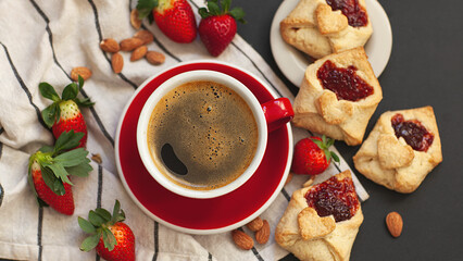 Homemade red jam heart cookies for Valentine's Day, with fresh strawberries, almonds and a cup of tea or coffee on a black background