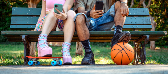 Young multiracial hipster couple using smartphone while standing sitting on the bench - Urban...
