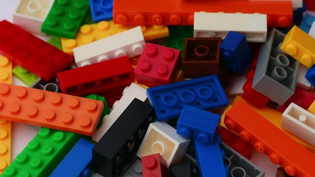 Multi-colored toys made of plastic cubes and bricks revolving on a turntable, children's constructor.The concept of the development of logic, children's creativity.Macro plan constructor, background.