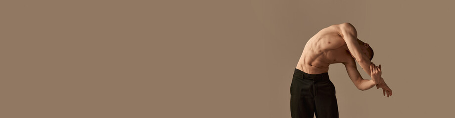 Fototapeta premium Portrait of handsome young redhead man posing shirtless in pants on grey studio background. Muscular body shape. Concept of men's health and beauty, body care, fitness. Banner. Copy space for ad, text