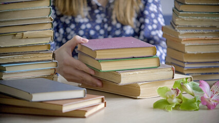 Obraz premium Hand turning pages of book. Flipping through and reading an old book on table in library. Concept of Reading and Education. Close up
