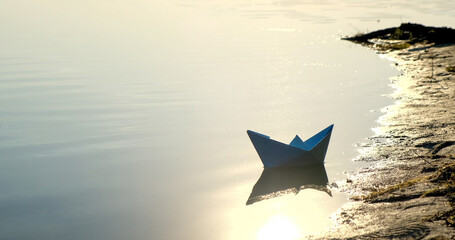 Ship made from paper swimming on water surface in evening or early morning.  Homemade paper boats...