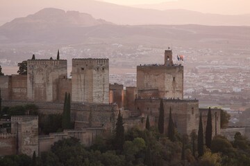 Photography of the Torre de la Vela (Alcazaba) of the Alhambra in Granada at sunset, orange colors, tourists...
