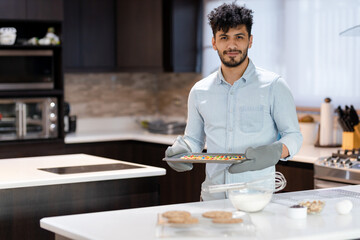 Fototapeta na wymiar Young Hispanic man baking homemade cookies - young man preparing cookies