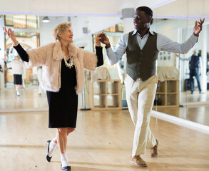 Man and senior woman dancing waltz in studio