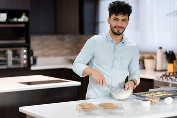 Fototapeta na wymiar Hispanic man preparing desserts in his home kitchen - Happy young man cooking