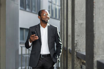 Portrait of a smiling confident and successful African American businessman in a suit and glasses...