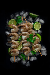 Frozen raw shrimp vannamey, on wooden skewers, ice cubes and lime slices, top view, no people,