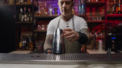 A charismatic bartender starts preparing a cocktail. the man takes the shake and tosses it. High quality 4k footage