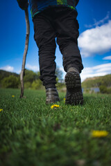 Rear and bottom view of the shoes of a person trekking in Patagonia with a walking stick.