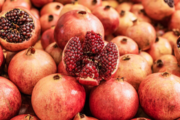 Fototapeta na wymiar Juicy ripe Pomegranate fruit, Punica granatum. Whole and cut open fruits on display market counter