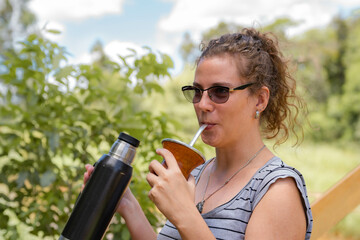Young girl drinking hot mate outdoors enjoying nature in the park.