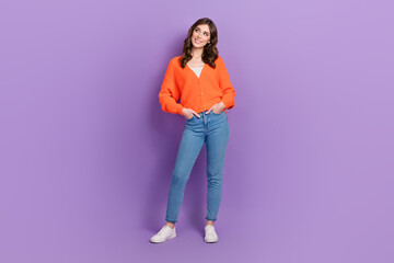 Full body photo of attractive gorgeous lady wear stylish outfit hands pockets look empty space advertisement isolated on purple color background