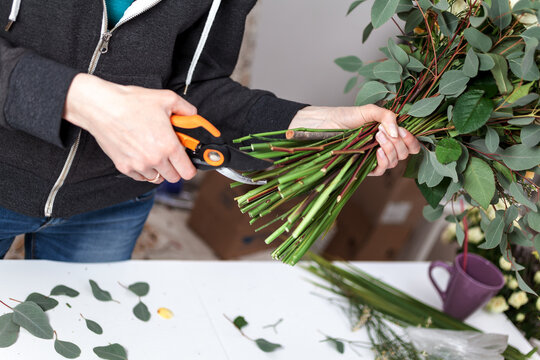 florist cuts the stems of flowers in a bouquet of pruning shears