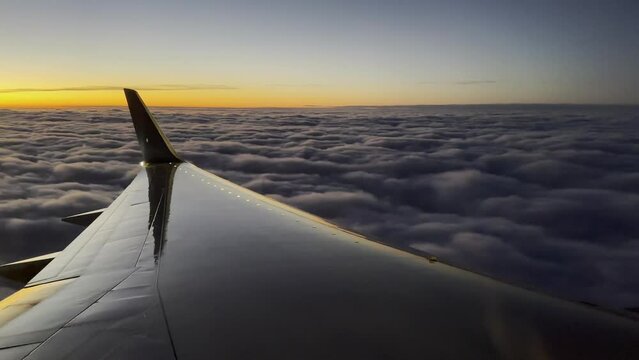 airplane descending into the clouds at sunset