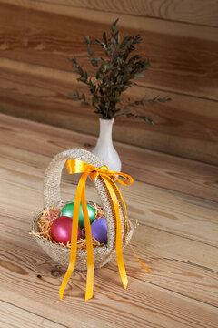 Easter basket filled with hand painted pastel Easter Eggs over white background. Next to vase with eucalyptus leaves.