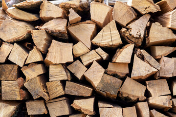 A pile of dry chopped firewood. Preparing for the winter. Harvesting firewood. Natural resources. Heating without gas. Background of dry chopped firewood. Wooden background. Natural texture.