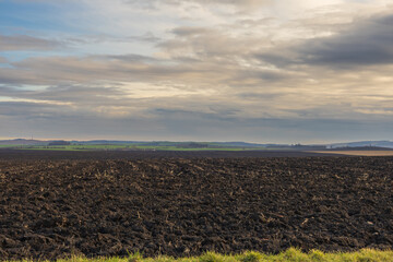Plowed field ready for sowing. There are clouds over the landscape.