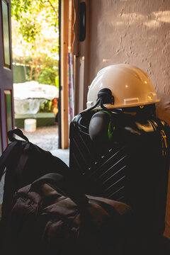 PPE (white safety helmet with attached earmuffs) over  a black suitcase and bags at the door in the day