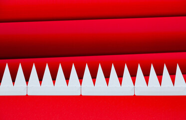 White triangular pointed teeth sticking out in a row of red, on a red striped background.