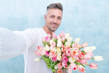 man with valentines tulips taking selfie photo isolated on blue background.