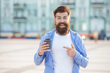 photo of guy offering coffee, point finger. guy offering coffee outdoor. guy offering coffee