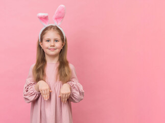Obraz na płótnie Canvas Little girl with bunny ears on pink background with copy space. Easter girl on pink background.