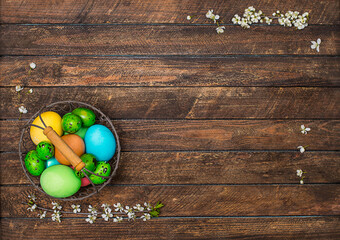 Easter colorful eggs in metal basket on wooden background with copy space.