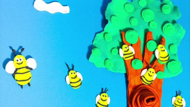 Stop motion animation from plasticine. Bees fly near a beehive on a tree in the forest. Claymotion cartoon.